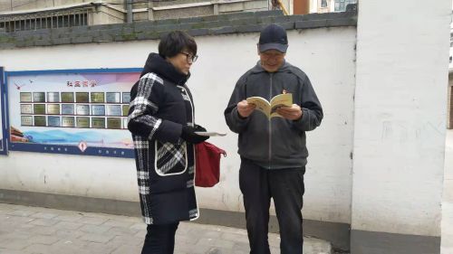 工作人员向居民发放创城知识手册