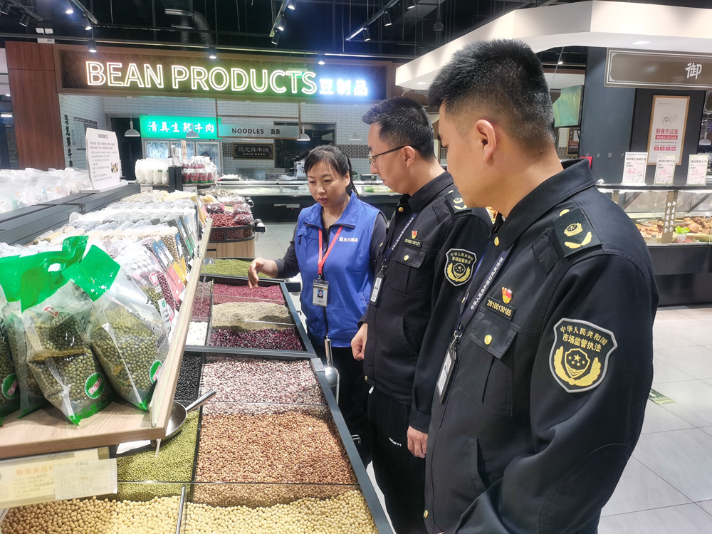 图为执法人员在超市检查散装食品标识标签、防尘措施、进货查验制度等落实情况  拍摄：何向阳