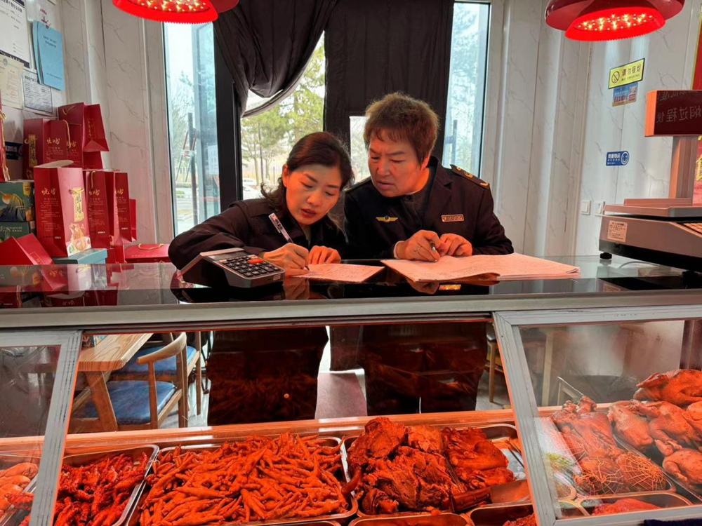 图为执法人员在卤肉店检查该店肉制品食品安全情况后反馈检查问题并下发监管记录 拍摄：冯亚宏