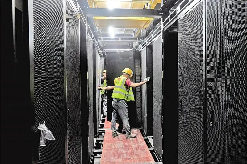 工人在中国移动（甘肃·庆阳）数据中心N01新型工业化数据中心安装机柜。
