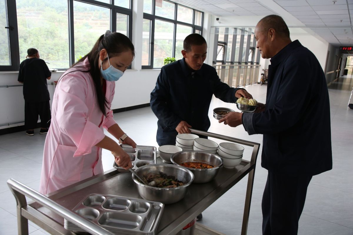 宁县社会福利院工作人员正在为特困人员盛饭