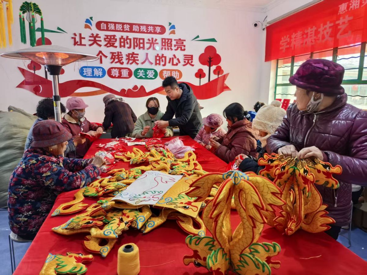 惠湘灵韵就业工厂车间内残疾人就业者缝制香包