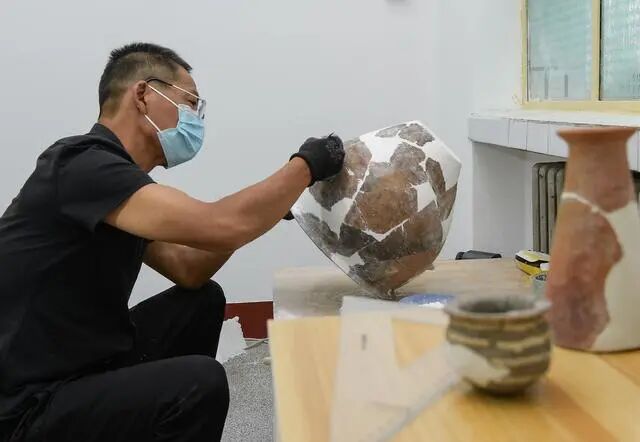 文物工作者對南佐遺址內(nèi)出土的陶器進行修復(fù)（2022年8月25日攝）二。新華社記者 李賀 攝
