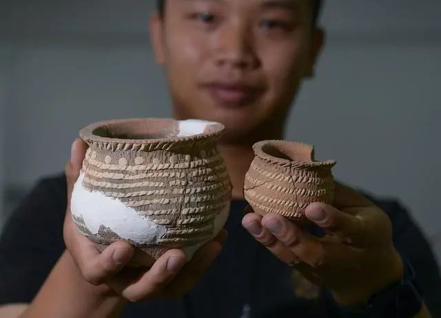 考古工作人員在展示遺址內(nèi)出土的箍白泥附加堆紋夾砂陶罐（2022年8月25日攝）。新華社記者 李賀 攝