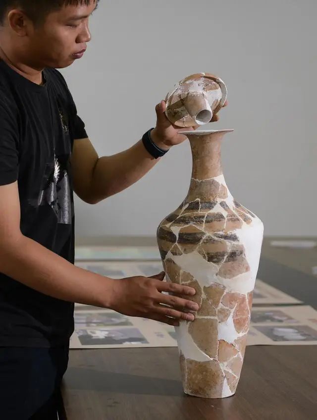 考古工作人員在展示南佐遺址內(nèi)出土的帶有蓋塞的彩陶小口細頸平底瓶（2022年8月25日攝）。新華社記者 李賀 攝