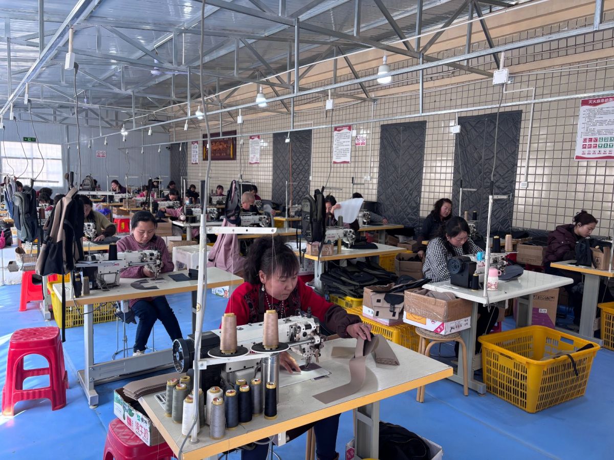 寧縣啟翔箱包就業(yè)工廠內(nèi)工人正在生產(chǎn)背包