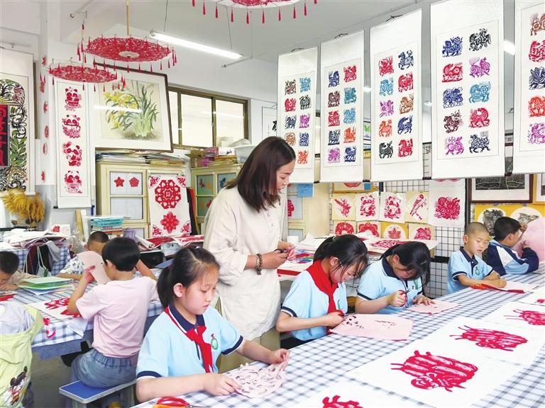 在天津市津南區(qū)培訓(xùn)歸來的靈臺縣城南小學(xué)美術(shù)教師周雪艷指導(dǎo)學(xué)生剪紙。（景潔）