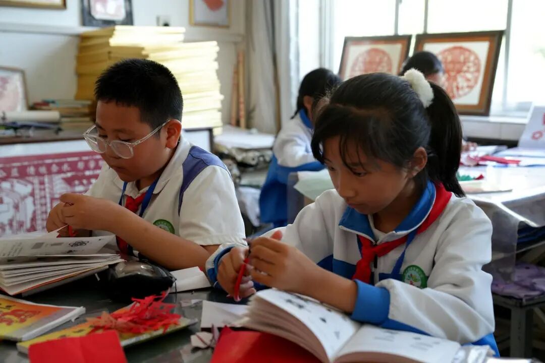 合水县西华池小学学生学习剪纸。