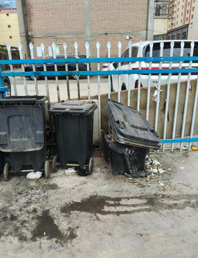 秦直路西北侧,商校家属院西侧小巷,垃圾桶烧毁,垃圾在垃圾桶旁乱扔。