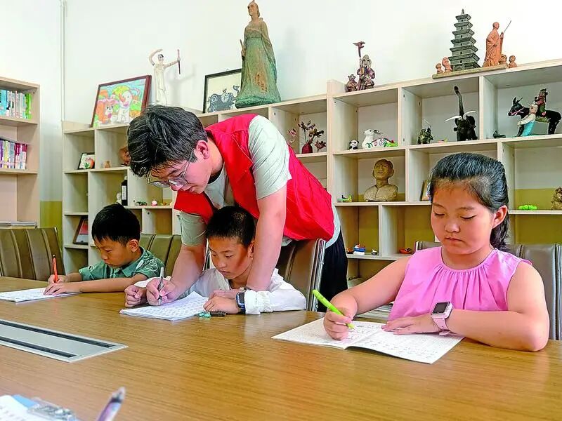 大学生志愿者在专署巷社区指导学生写硬笔书法。 通讯员 程娟娟 摄