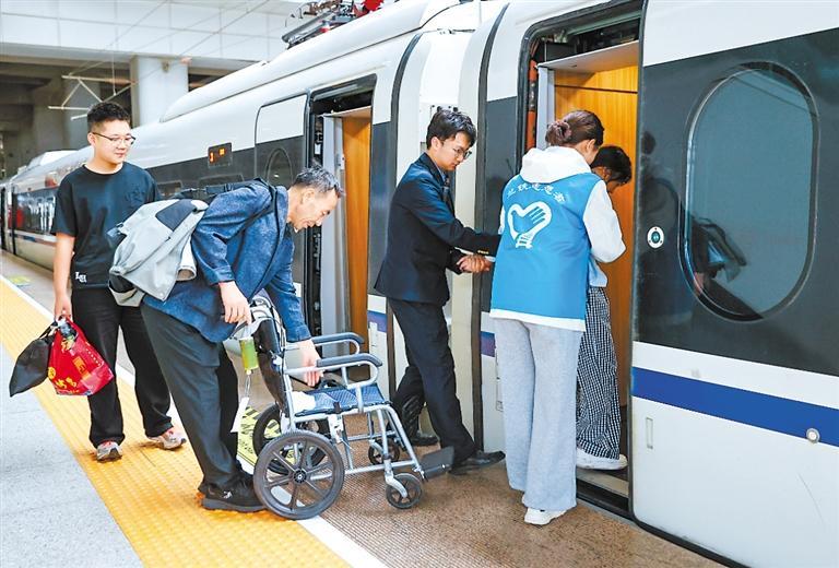 兰州西站工作人员与志愿者帮助行动不便旅客乘车。(通讯员宋佳龙)