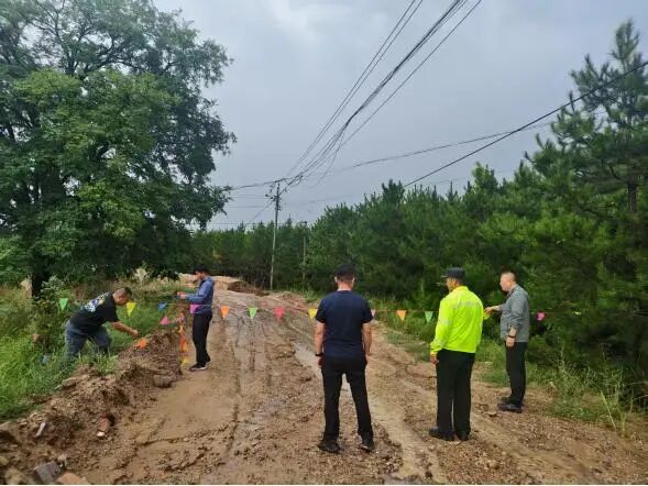 （图为：庆城县马岭镇、县交通局党员干部查勘水毁道路，并拉起警戒线。）