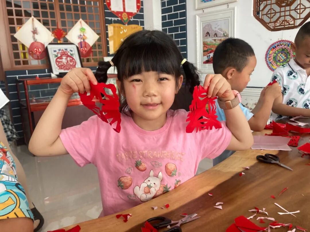 活动邀请国家级非物质文化遗产（庆阳剪纸）市级代表性传承人马路现场授课。传承人为孩子们讲述了剪纸艺术的起源与民俗寓意，现场示范折纸、镂空、裁剪等技法，逐一纠正孩子们的握剪姿势与裁剪细节。孩子们凝神创作，红纸翻飞间，一个个造型别致的窗花从手中&ldquo;绽放&rdquo;开来。