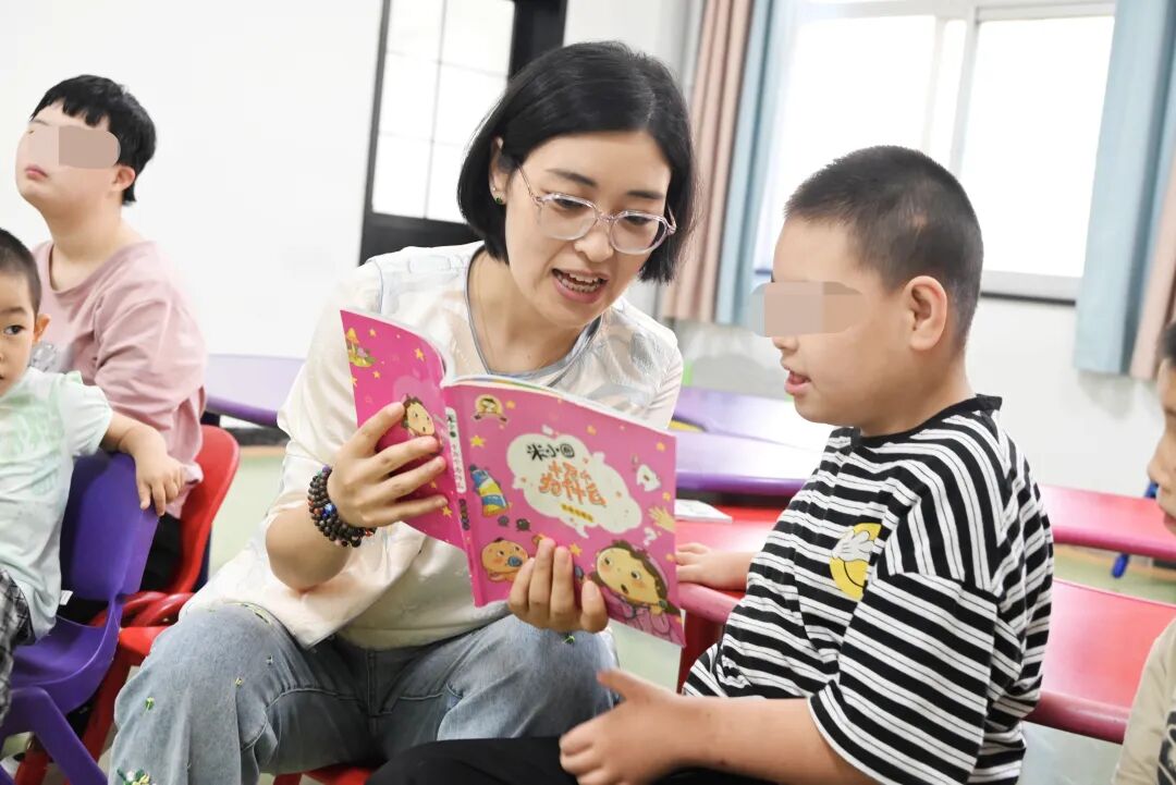 图为甘肃省庆阳市儿童福利院特教老师给代养儿童讲故事