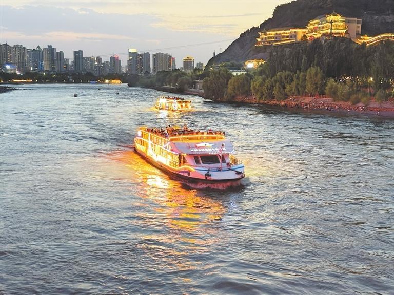 游客乘坐观光游船，欣赏兰州黄河两岸夜景。
