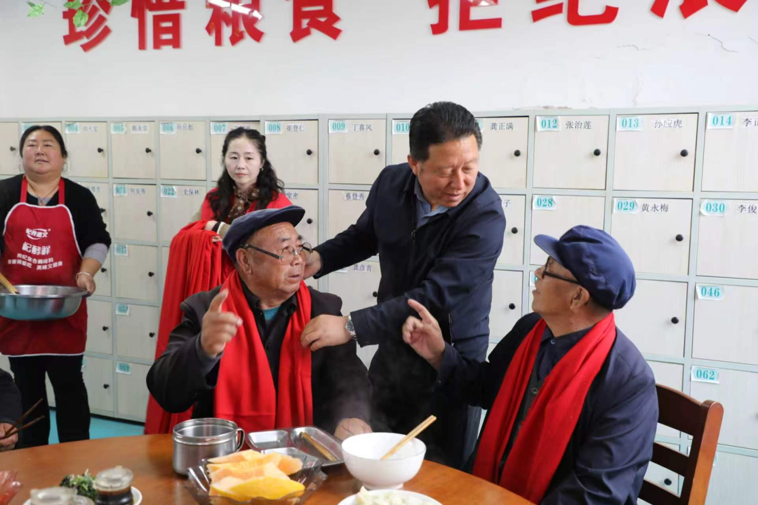 洪德镇党委书记、新时代文明实践所所长张会星为敬老院老人系上红围巾,并陪老人共进重阳餐。
